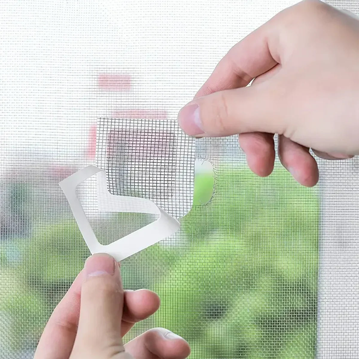 Applying adhesive patch to repair window screen mesh, hands holding repair patch close-up